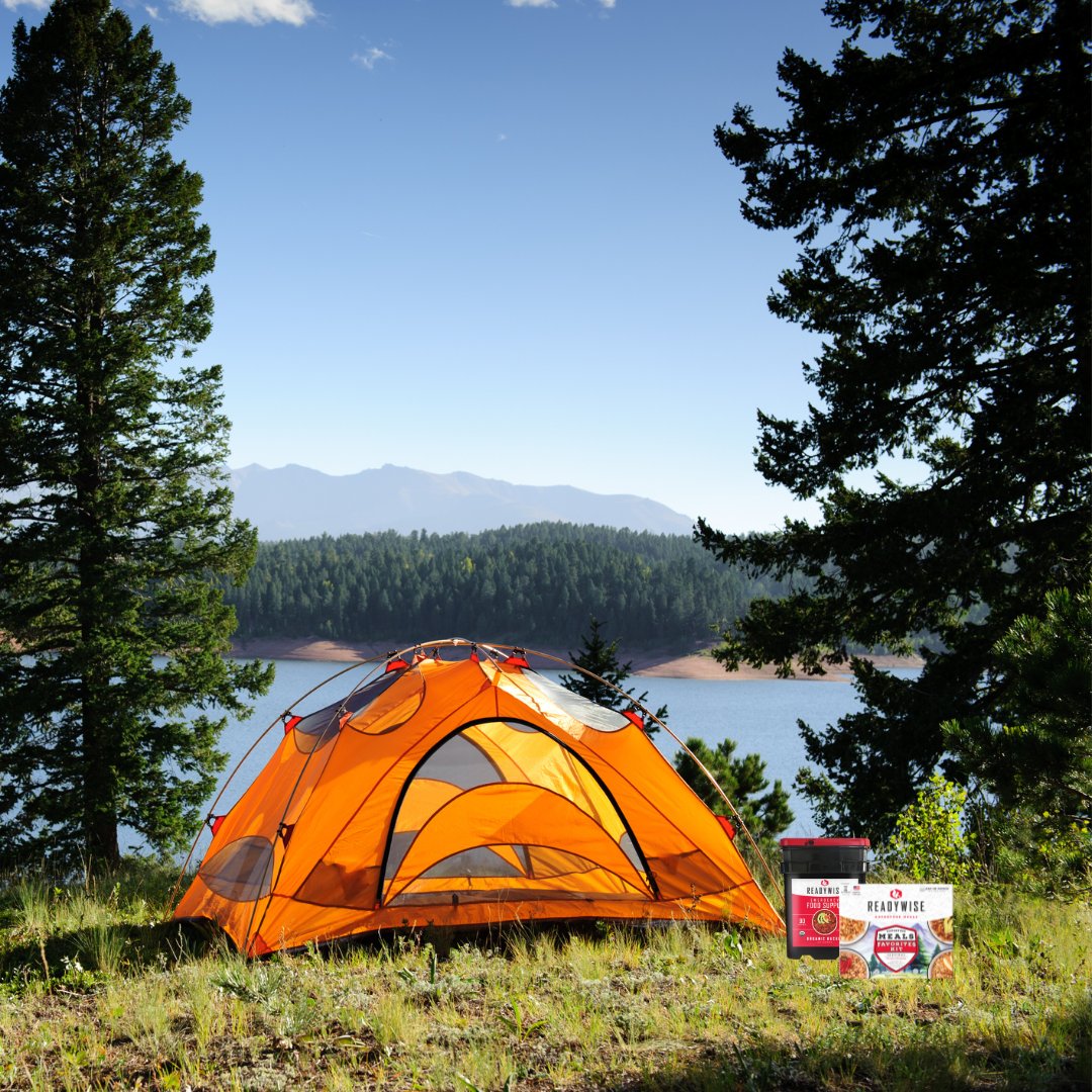 Tent between trees with a lake in the background